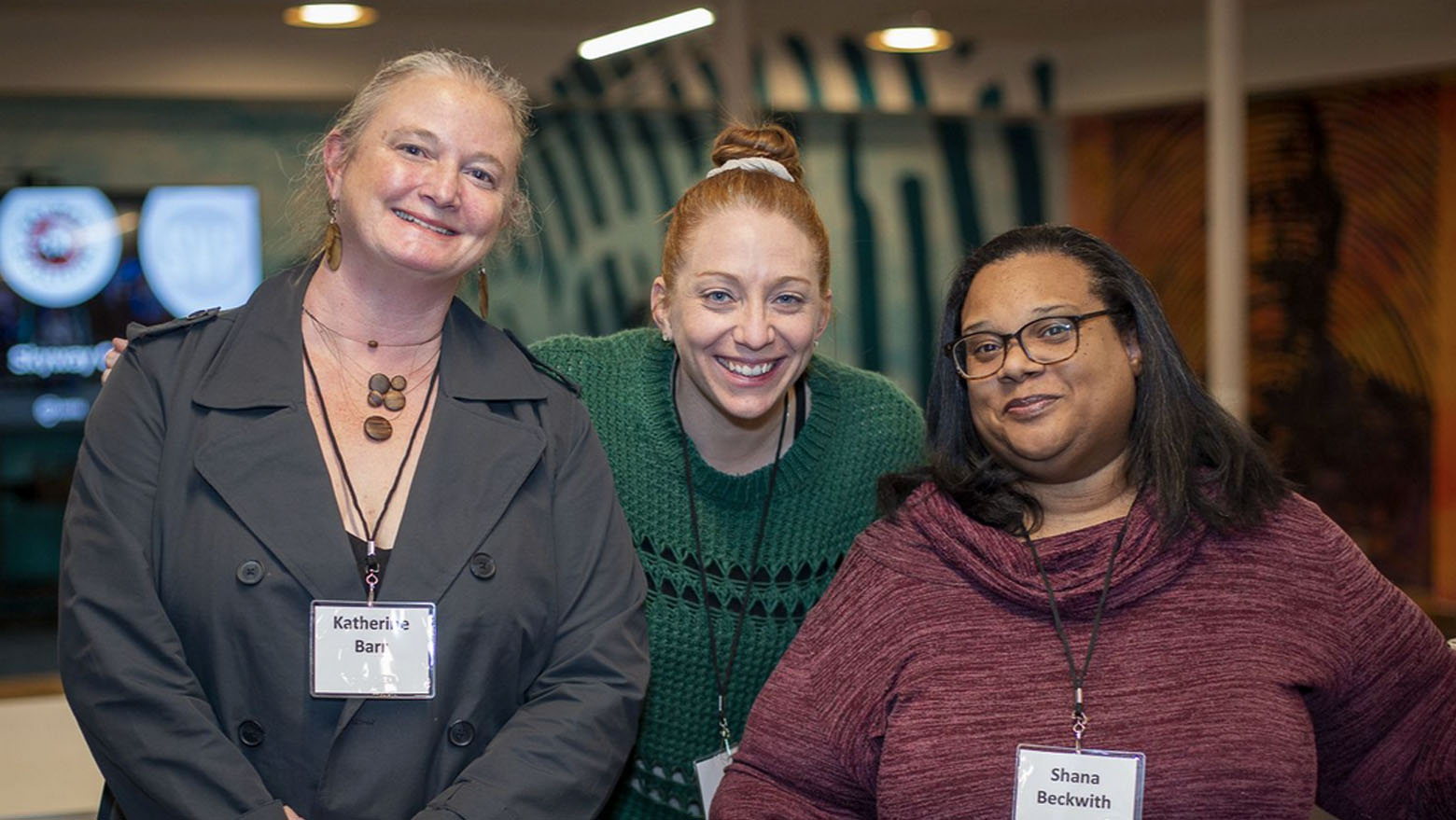 Inaugural cohort Three members wearing name lanyards, smiling at the camera